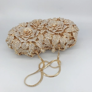 Close-up of golden hollow rose evening clutch with sparkling rhinestones and chain