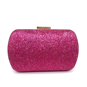 Detail view of rose red clutch bag featuring sparkling sequins and a golden metal clasp