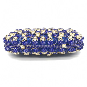 Détail macro de la pochette bleu roi avec strass et motif de crâne en métal doré