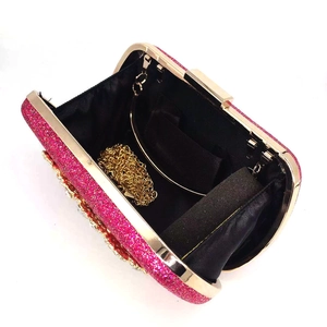 Detail view of fuchsia sequin clutch bag with golden chain and black fabric interior