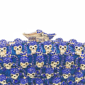 Gros plan de strass bleus et de crânes dorés sur une pochette de soirée de luxe