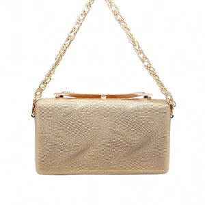 Detail view of golden evening clutch with wavy 3D texture and metallic chain strap