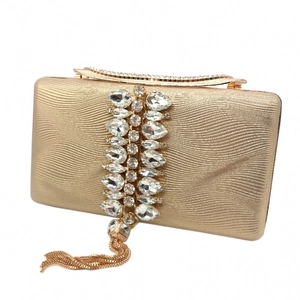Detail of evening clutch with wave texture fabric, rhinestone inlay, and gold chain tassels