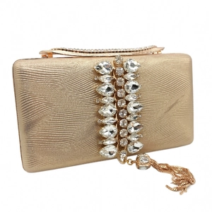 Detail of champagne gold evening clutch with pleated texture, tassels and crystal brooch