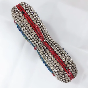 Detailed macro view of crystal evening clutch bag with blue and red gemstone accents