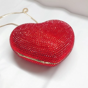 Detail der roten herzförmigen Clutch mit funkelnden Kristallen und goldener Kette