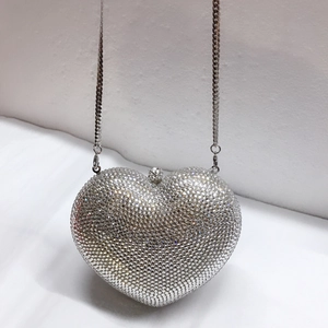 Nahaufnahme der silbernen Herz-Abendtasche mit Metallkette und funkelnden Strasssteinen