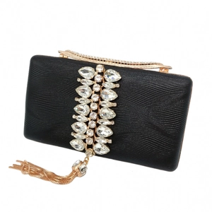Detail of black evening clutch featuring sparkling crystal cluster and golden fringe tassels
