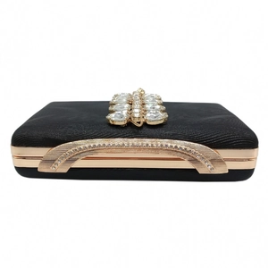 Macro shot of luxury black evening clutch featuring crystal clusters and gold metal frame
