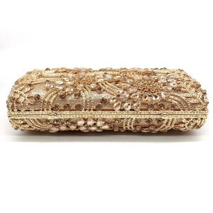 Close-up of golden evening clutch featuring champagne crystals and floral rhinestone patterns