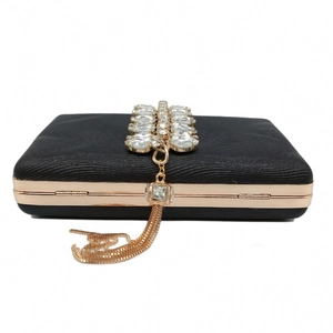 Detail of black evening clutch with rhinestone top and rose gold tassel fringe