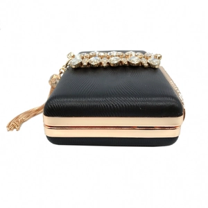 Detail of black satin evening clutch with gold metal frame, rhinestones and fringe tassel