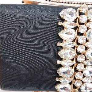 Detail view of black textured fabric and premium rhinestone accents on evening clutch