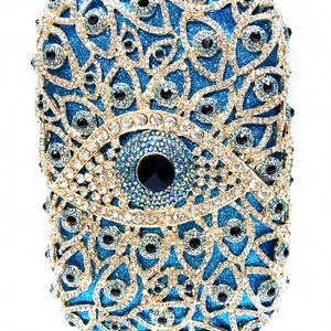 Detaillierte Makroansicht des kristallbesetzten Evil-Eye-Musters auf der blauen Abendtasche