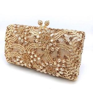 Close-up of golden evening clutch with intricate floral rhinestones and carved clasps