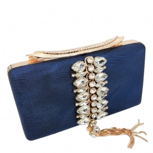 Close-up of navy blue evening bag with gold metal frame and sparkling crystal tassels