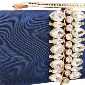 Detail of navy satin clutch featuring luxury wavy texture and sparkling rhinestone fringe