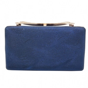 Detailed view of the wavy texture and ornate gold clasp on a navy blue evening clutch bag
