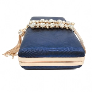 Detail of dark blue evening bag with gold metal frame, rhinestones and tassel charms