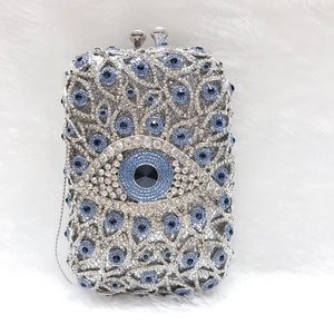 Detailansicht der Evil-Eye-Kristall-Clutch mit Silbermetallrahmen auf weißem Kunstfell