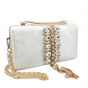 Detail of white evening clutch featuring large crystals, gold hardware, and tassel