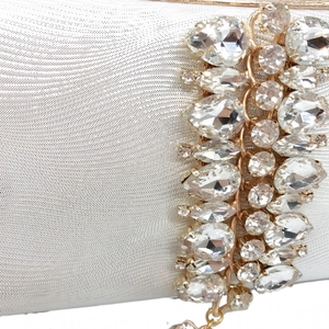 Macro shot of silver evening bag featuring wavy textured fabric and luxury crystal accents