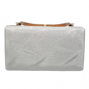 Close-up of silver evening clutch bag with wave texture and gold metal handle