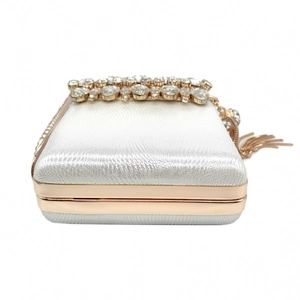 Detail of white satin evening bag with rhinestone border and gold metal tassel charm