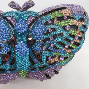Macro shot of colorful rhinestones and ruby crystal details on pink butterfly evening bag