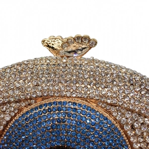 Close-up of butterfly clasp and blue crystal accents on a sparkling evening clutch bag