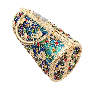 Detailed view of hollow gold metal evening bag with vibrant crystals and emerald silk base