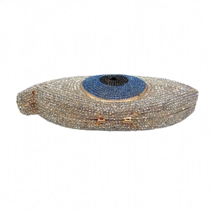 Macro view of crystal-encrusted evil eye evening bag with gold metal frame detailing