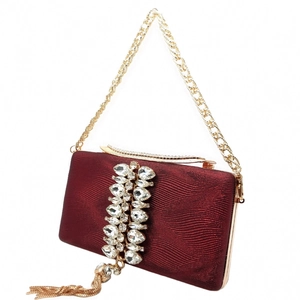 Close-up of red evening clutch with wavy texture, rhinestones and luxury gold tassels