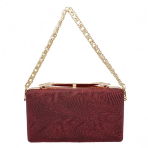 Detail of burgundy evening clutch bag with ripple texture and gold chain strap