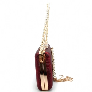 Detail of burgundy evening clutch featuring gold tassels, side rhinestones and metal chain