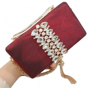 Detail of burgundy evening clutch bag with sparkling crystals and golden tassels