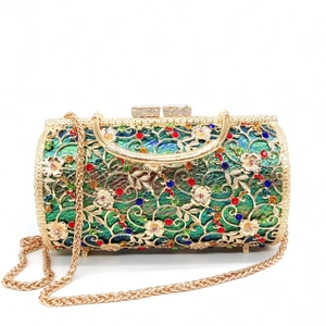 Detailed view of cylindrical gold evening bag with floral metal cutout and rhinestones