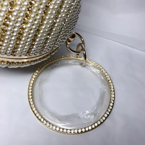 Détail macro du sac de soirée sphère avec perles incrustées, cristaux et poignée dorée