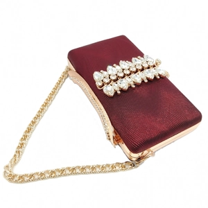 Detailed macro of burgundy evening clutch bag with sparkling rhinestones and gold chain