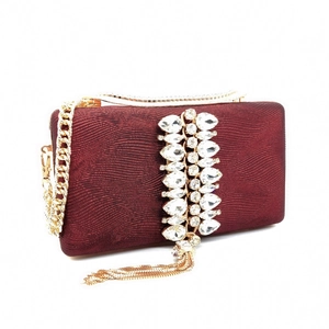 Detailed view of wine red evening bag with sparkling rhinestones and gold tassel chain
