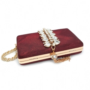 Detail of burgundy evening clutch with crystal rhinestones and golden tassel fringe