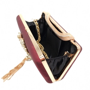 Macro shot of burgundy dinner clutch bag showing black interior lining and gold chain strap