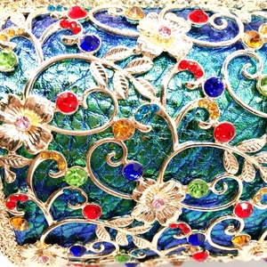 Macro detail of hollow gold metal pattern with multicolor rhinestones on evening clutch