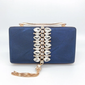 Close-up of deep blue textured evening clutch with sparkling rhinestones and gold tassels