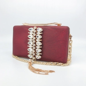 Detail of burgundy evening clutch with sparkling rhinestones, gold chain and tassels