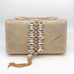 Detailed macro of champagne gold evening bag featuring luxury crystals and gold metal tassels