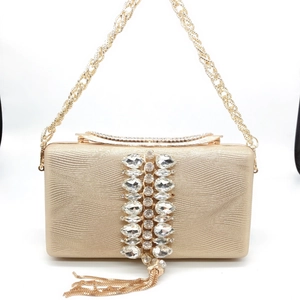 Detail of gold evening clutch featuring wave texture, rhinestones, and metallic fringe