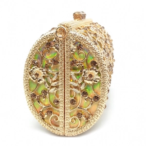 Macro view of gold hollow floral evening clutch featuring brown rhinestones and iridescence