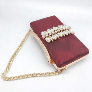 Detailed close-up of burgundy evening clutch with crystal tassels and gold metal frame