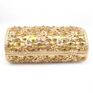 Close-up of golden hollow evening bag with floral metalwork and sparkling rhinestones